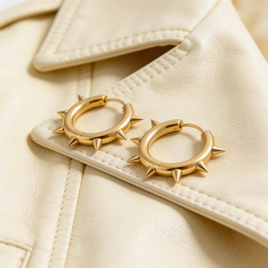 Gold hoop earrings with spike details on a beige jacket