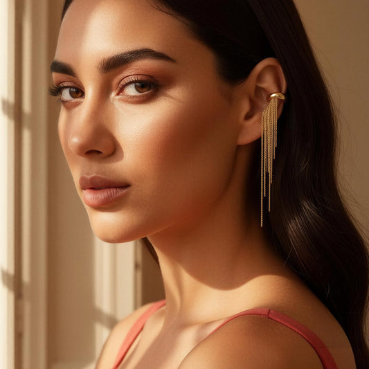 Woman wearing the Vela Gold Ear Cuff in front of a window with soft lighting