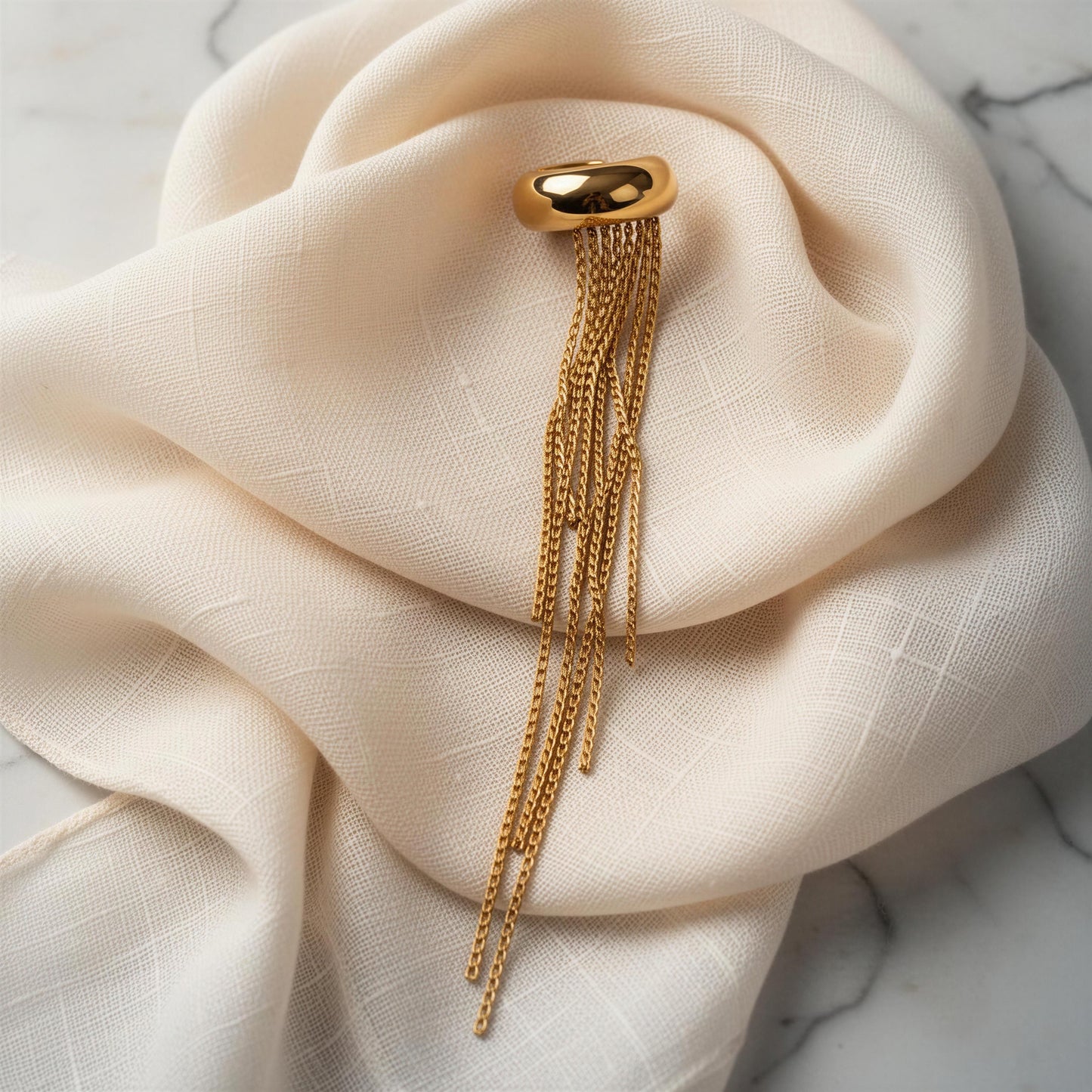 The Vela Gold Ear Cuff on a beige fabric background