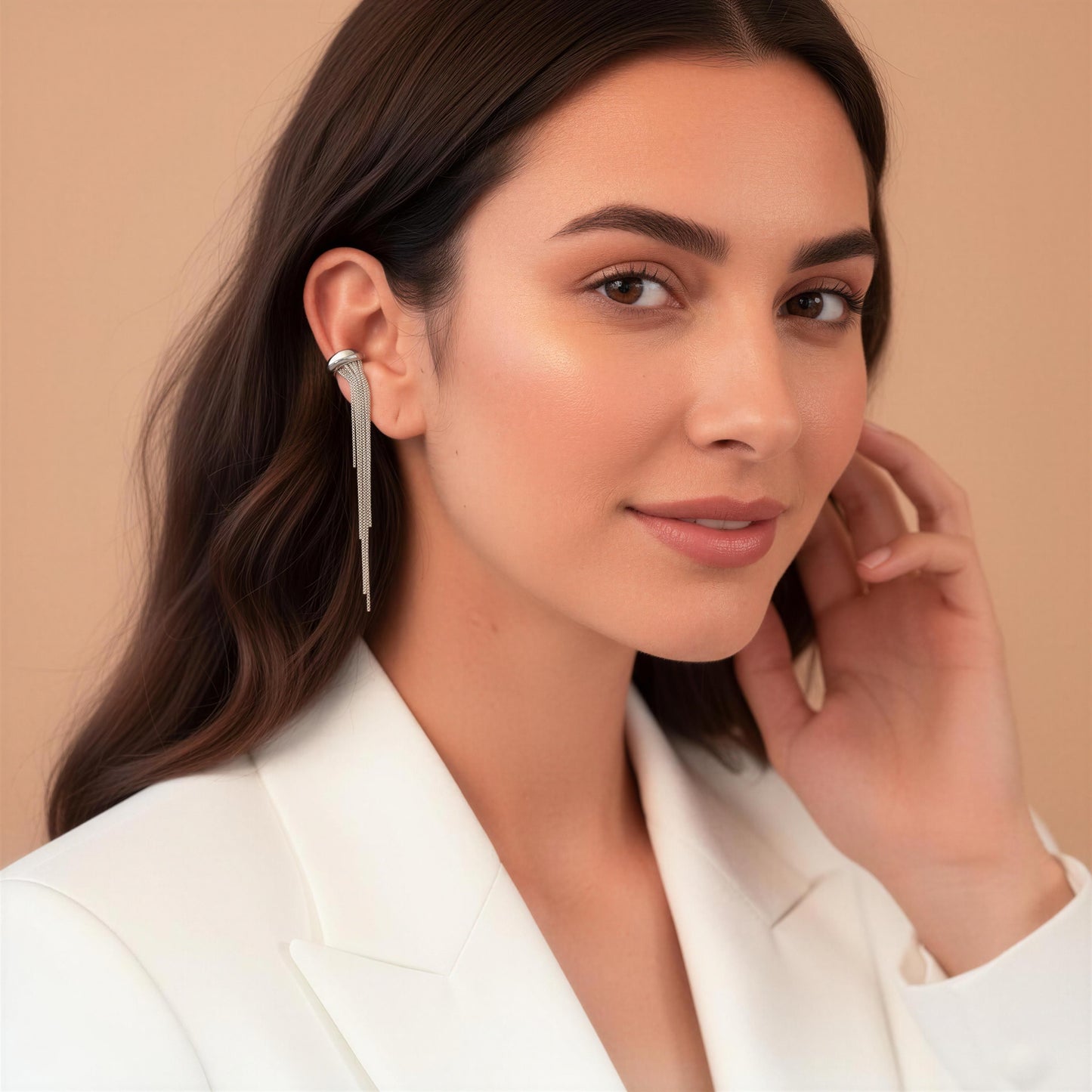 Woman wearing a silver earring against a beige background