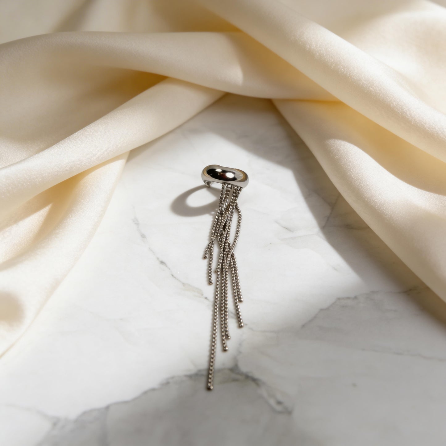 The Vela Silver Ear Cuff on marble table