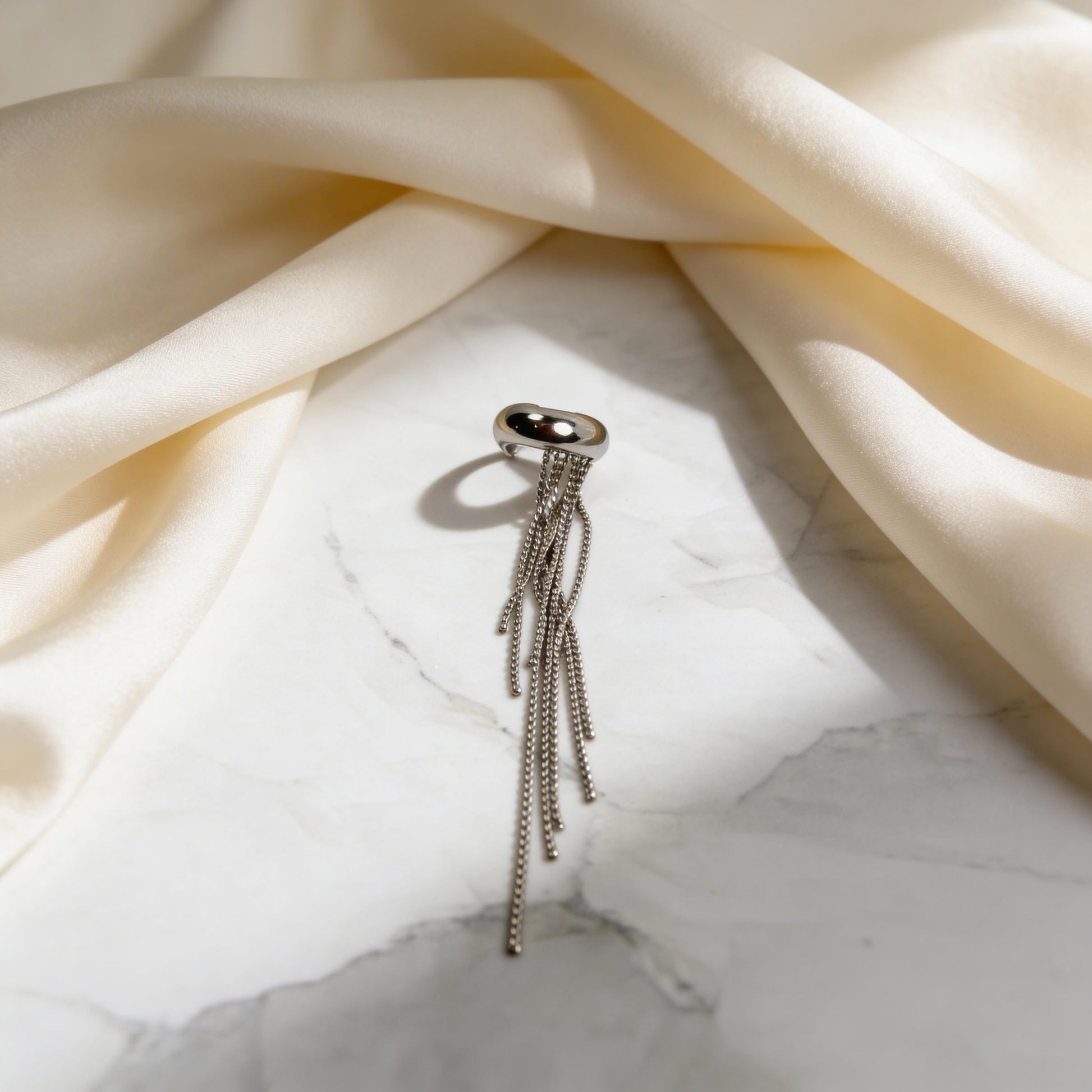 The Vela Silver Ear Cuff on marble table