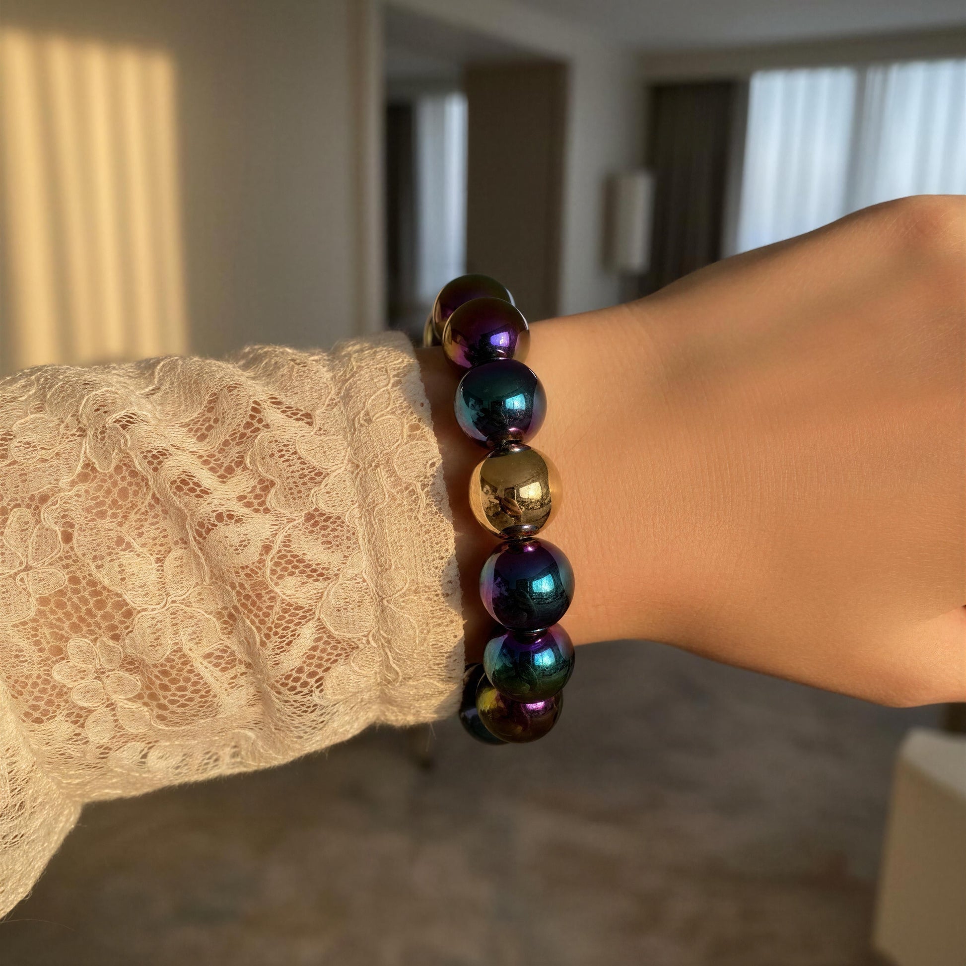 The Velvet Plum Bracelet on a wrist with lace sleeve in an indoor setting