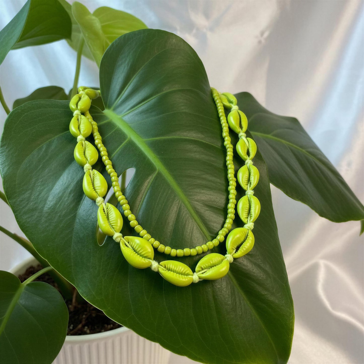 Necklace with green shell-like beads on a leafy background