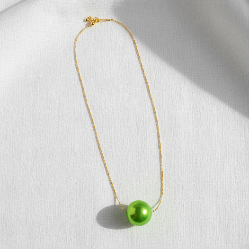 The Verde Petite Sphere Necklace with a green pendant on a white background