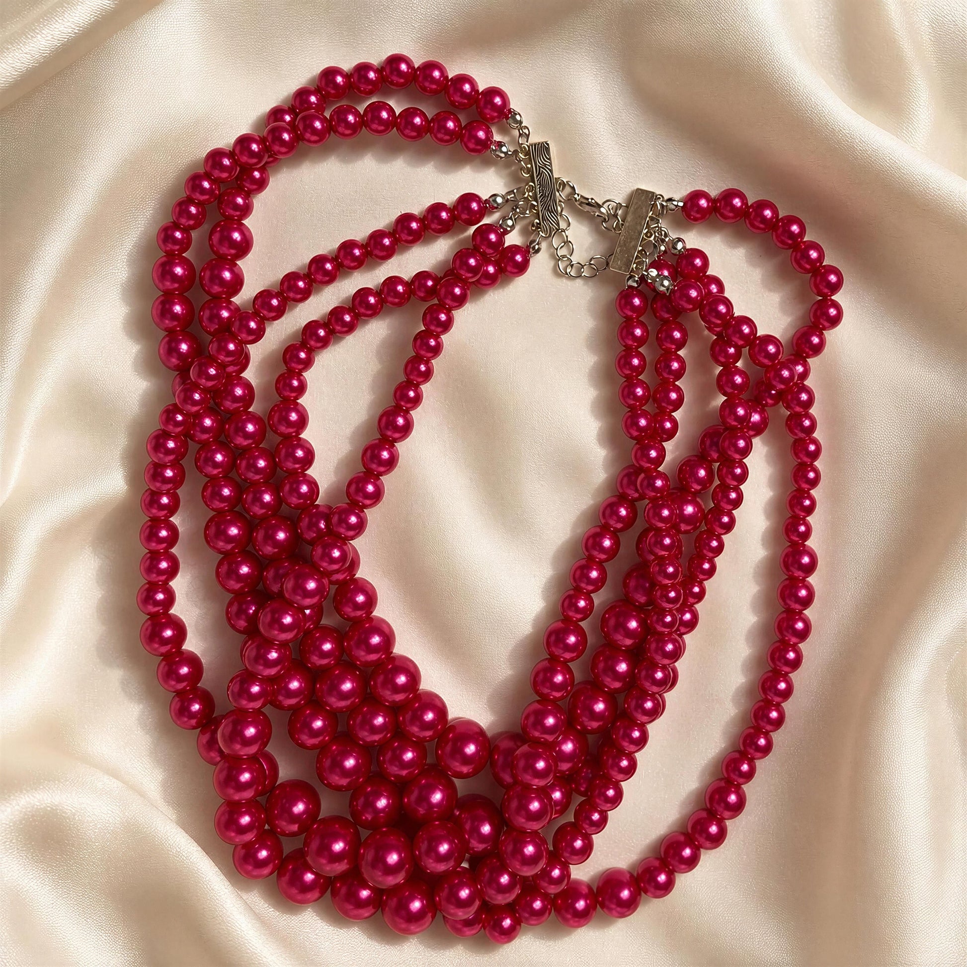 The Vienna Rose Pearl Cascade Necklace on a beige fabric background