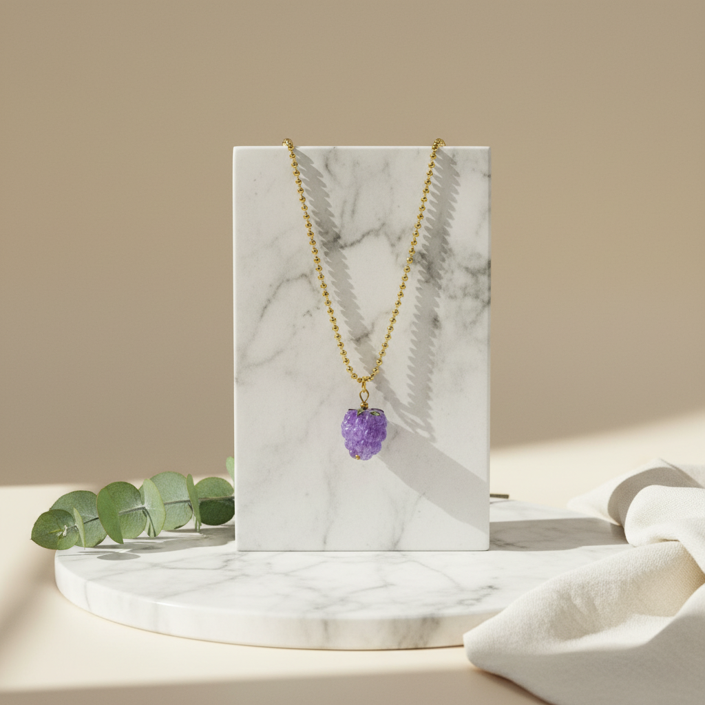 The Vigna Grape Pendant Necklace on a marble stand with a beige background