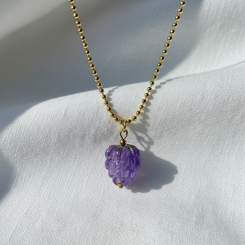 The Vigna Grape Pendant Necklace on a white fabric background