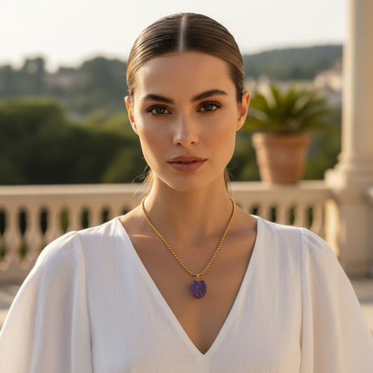 Woman wearing a gold necklace with a purple pendant outdoors