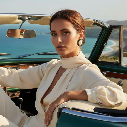 Woman sitting in a vintage car by the ocean with mountains in the background