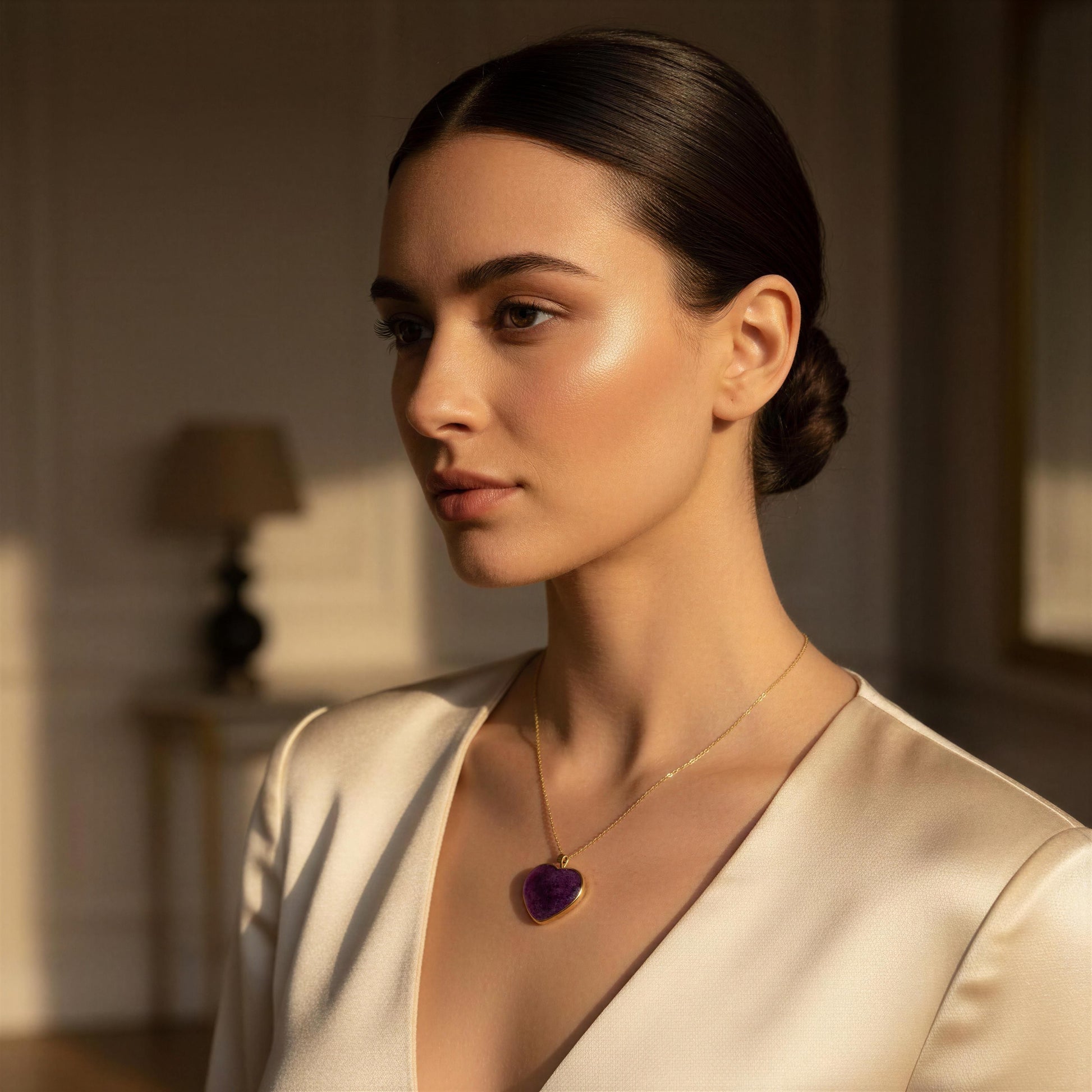 Woman wearing the Viola_Heart_Necklace with a purple pendant in a softly lit room.