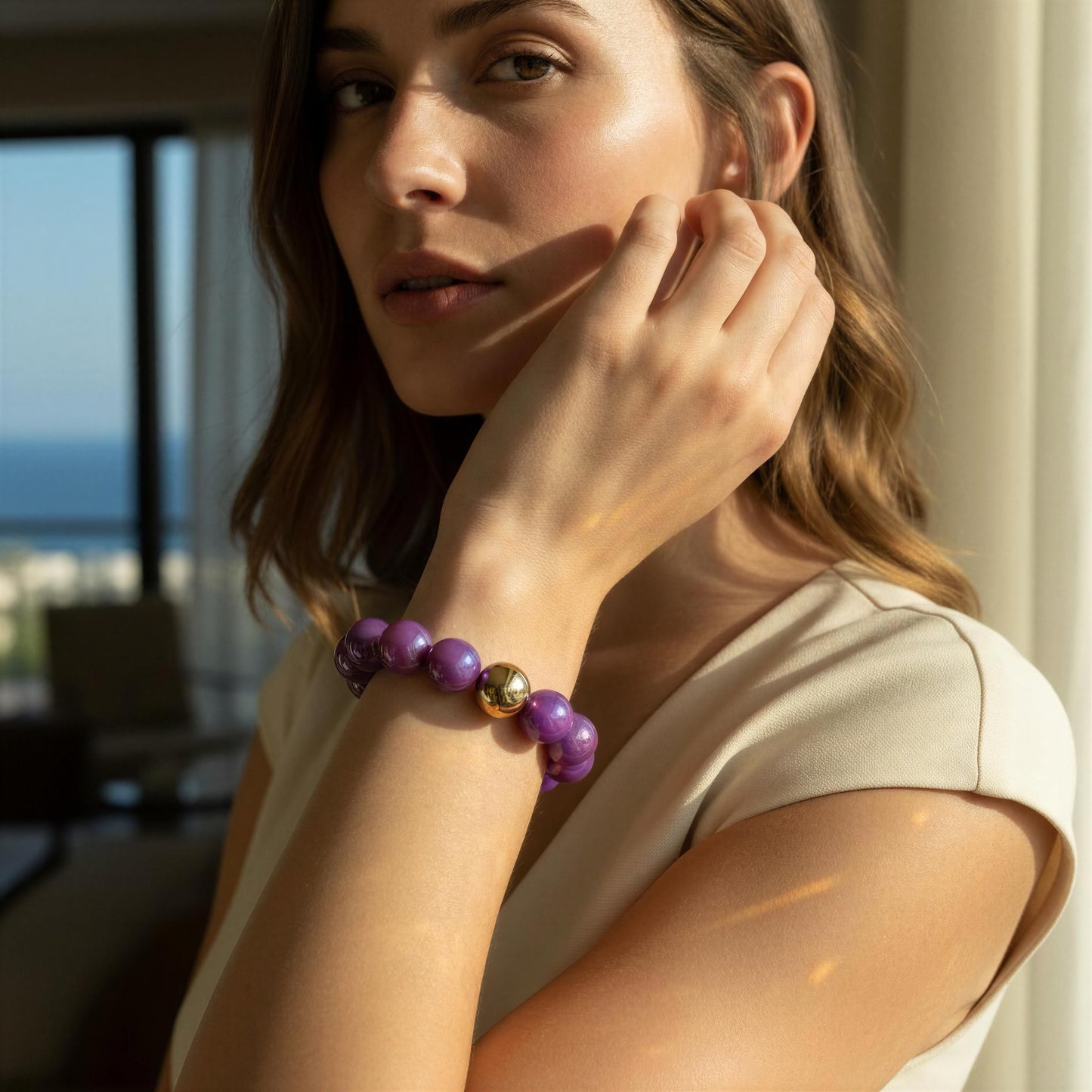 Woman wearing the Violeta Glow Bracelet in a room with a view of the ocean.