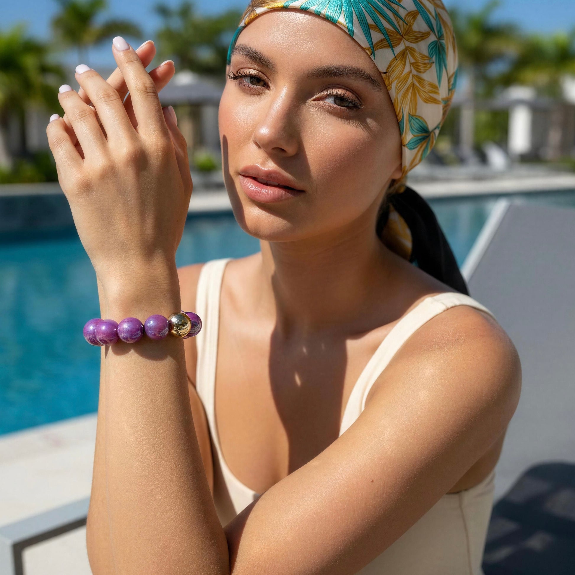Woman wearing a colorful headscarf and the Violeta Glow Bracelet  in poolside
