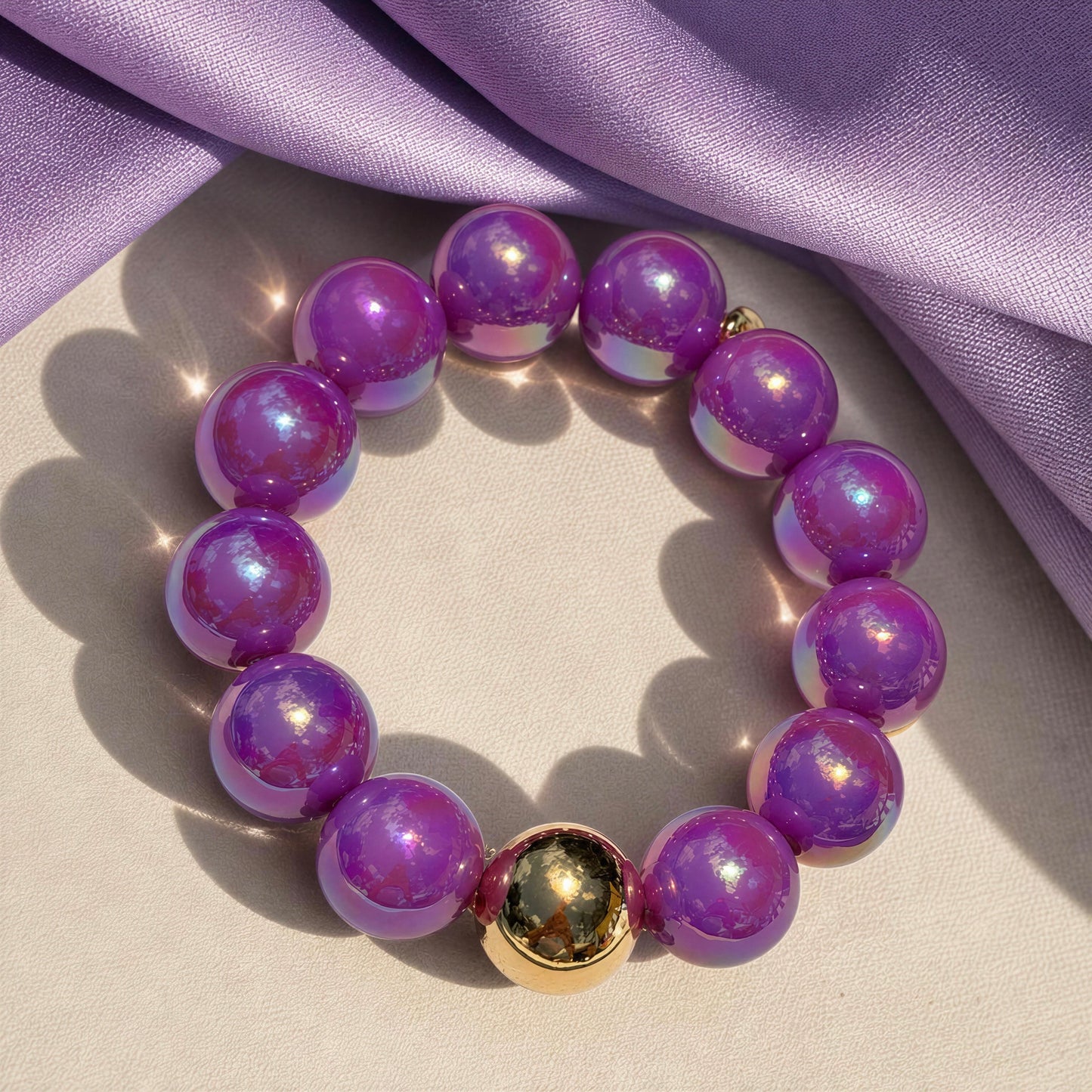 Purple beaded bracelet with a gold accent on a light background